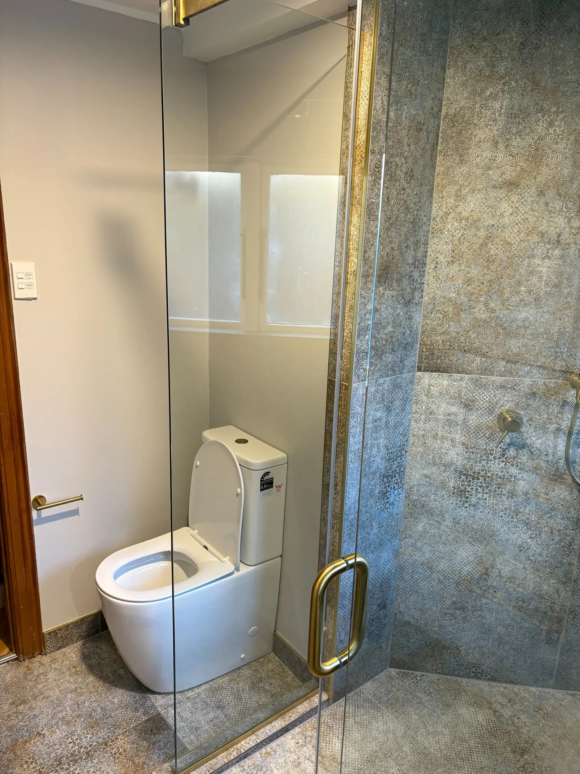Walk-in tiled shower with brass fittings after renovation