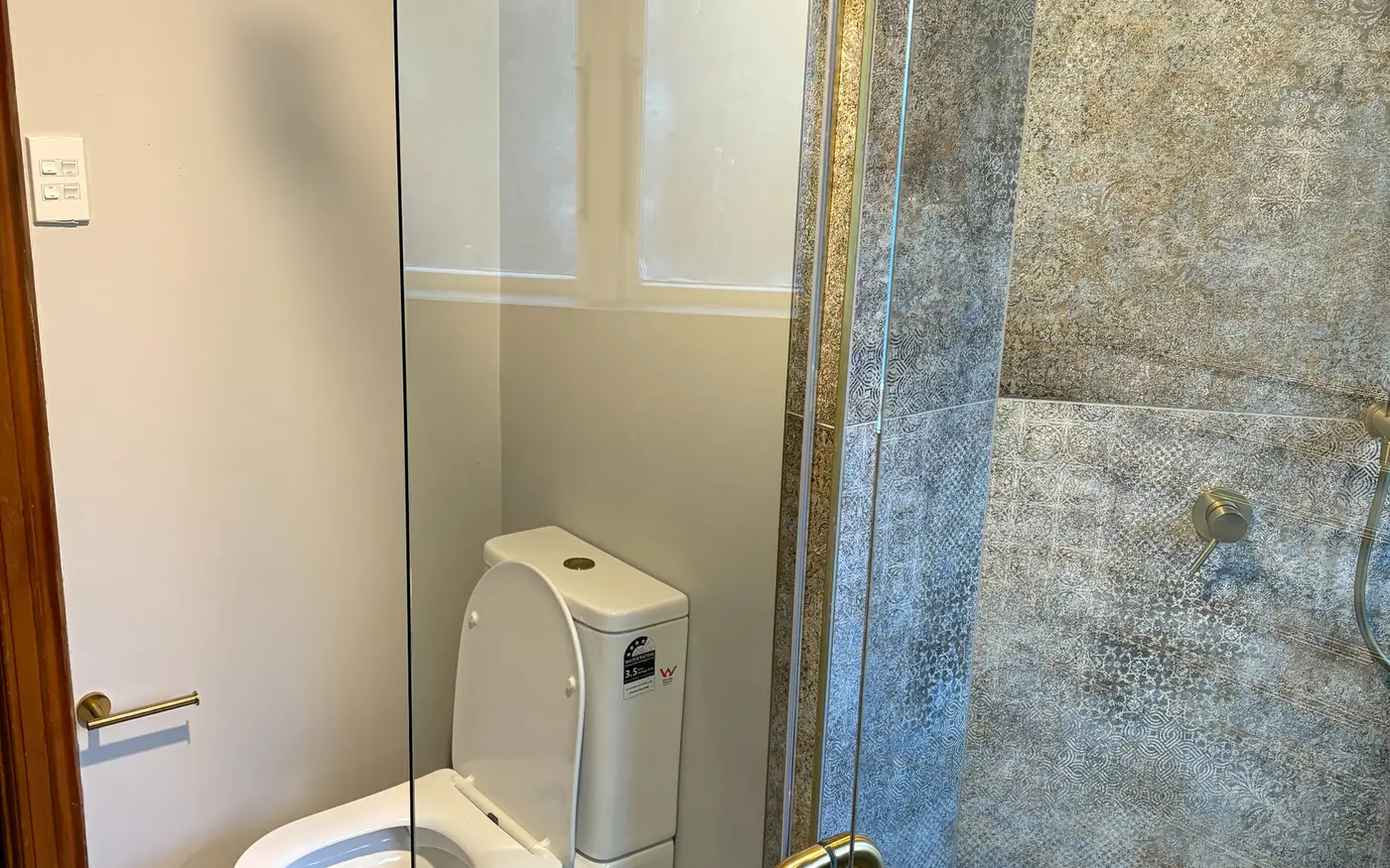 Walk-in tiled shower with brass fittings after renovation