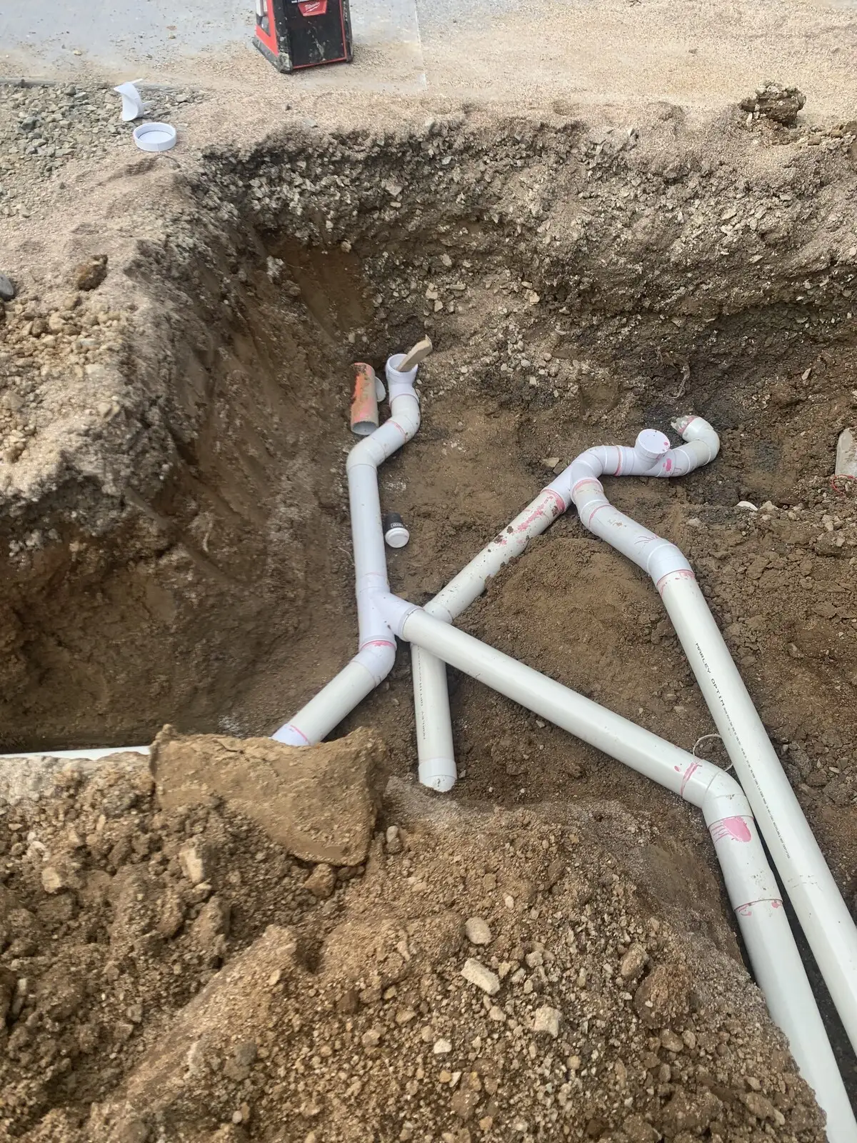 Broken drain exposed and relaid in an open trench