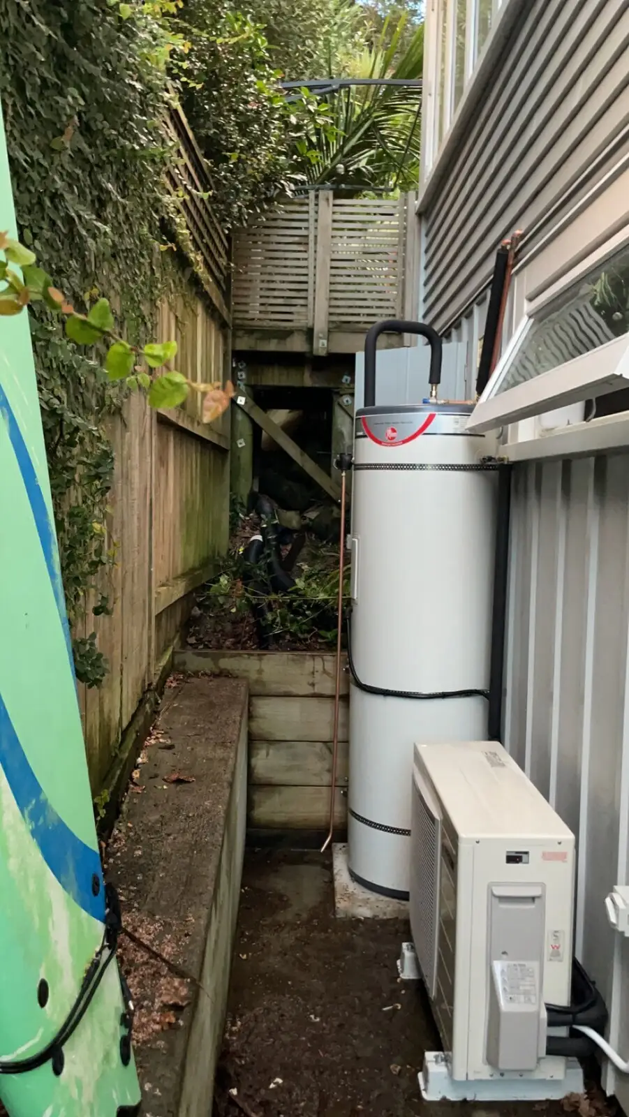 Heat pump hot water unit installed beside a house
