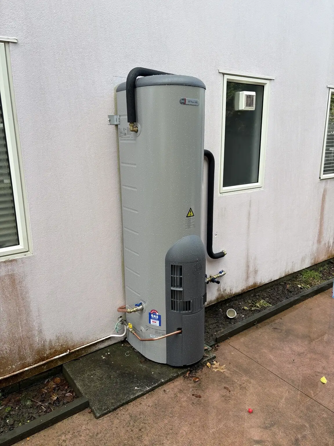 New outdoor hot water cylinder installed against a house wall