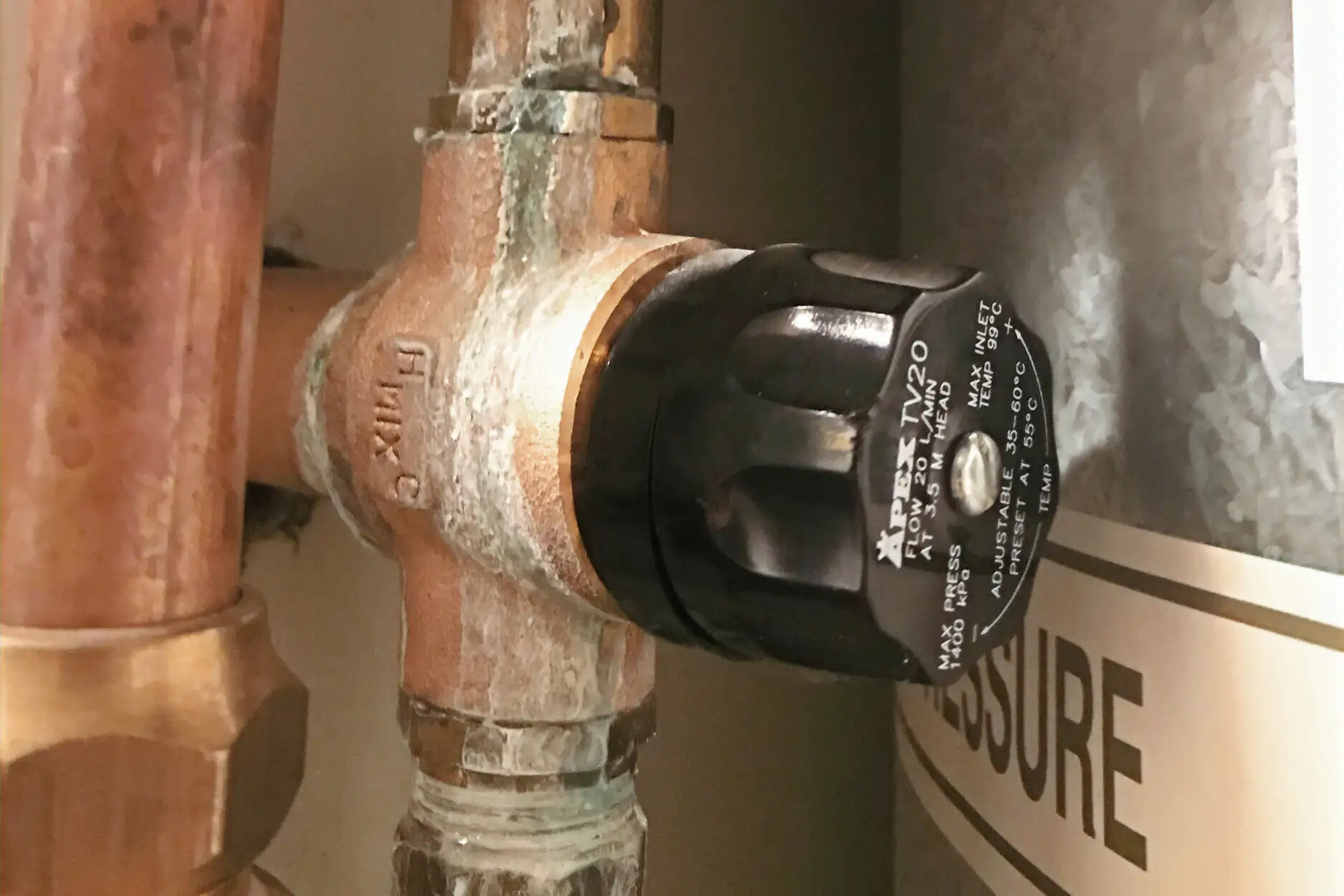 An Apex tempering valve on the copper pipework beside a mains pressure hot water cylinder