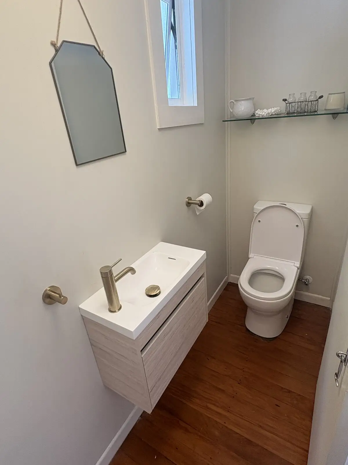 After: powder room with a new wall-hung vanity, brass tapware and new toilet
